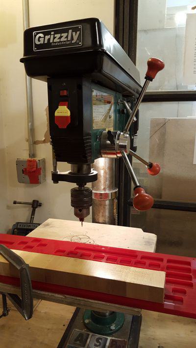 drill press machine, about to drill a hole through the acrylic piece that was previously laser cut.