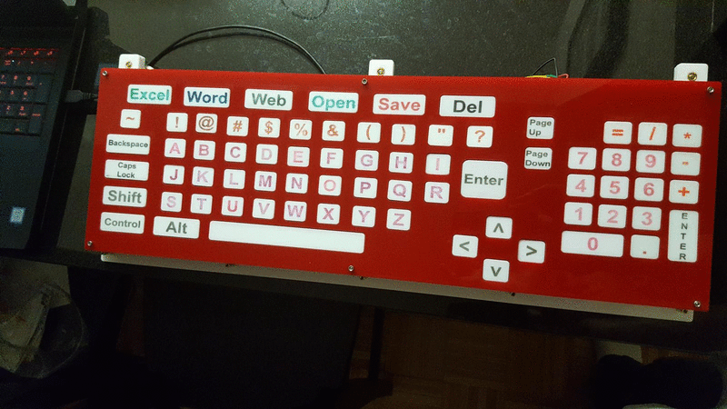 computer keyboard with large square buttons arranged in a grid pattern in alphabetical order. Non-alphanumeric characters are across the top and a number pad on the right.