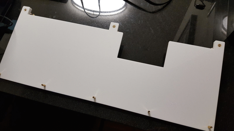 white acrylic sheet on table propped up a small angle by three metal feet on the top edge, causing the acrylic sheet to be at a small angle relative to the table.