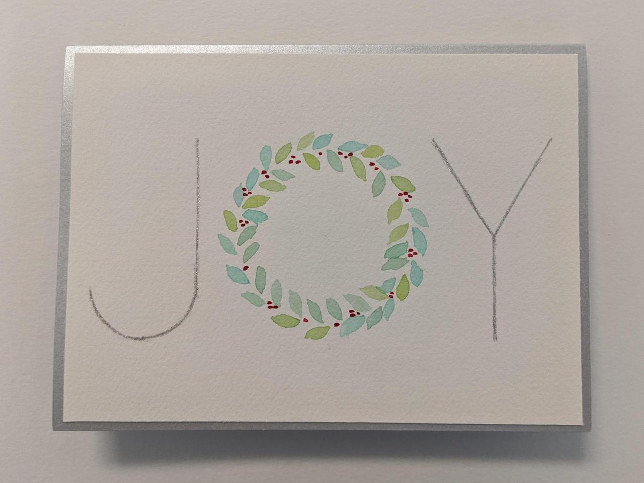 holiday card that has the word JOY on the front, with the letter "O" replaced with a wreath.