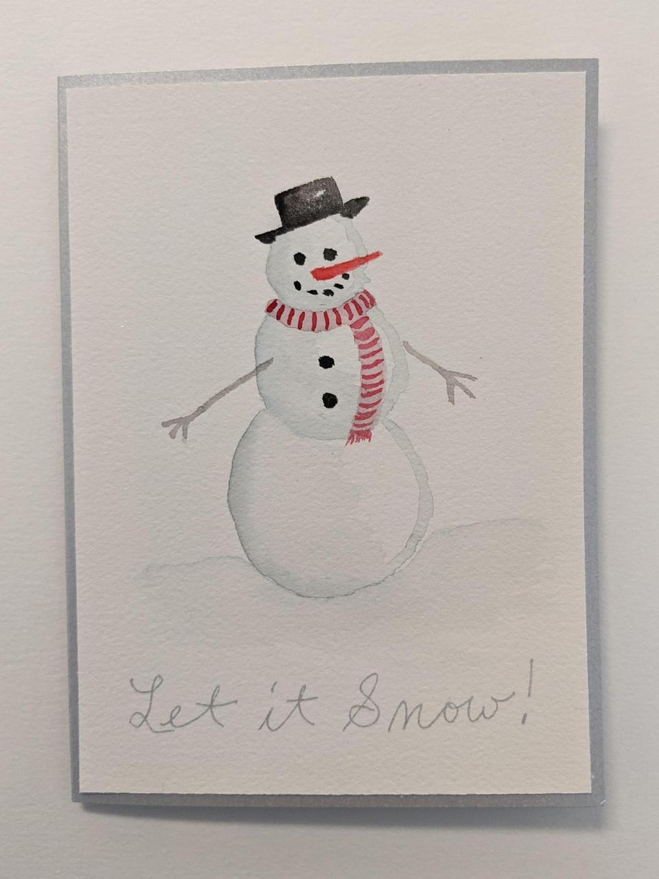 holiday card with a painting of a snowman on the front, with a carrot nose and coal eyes and mouth. It says "Let it Snow" across the bottom.