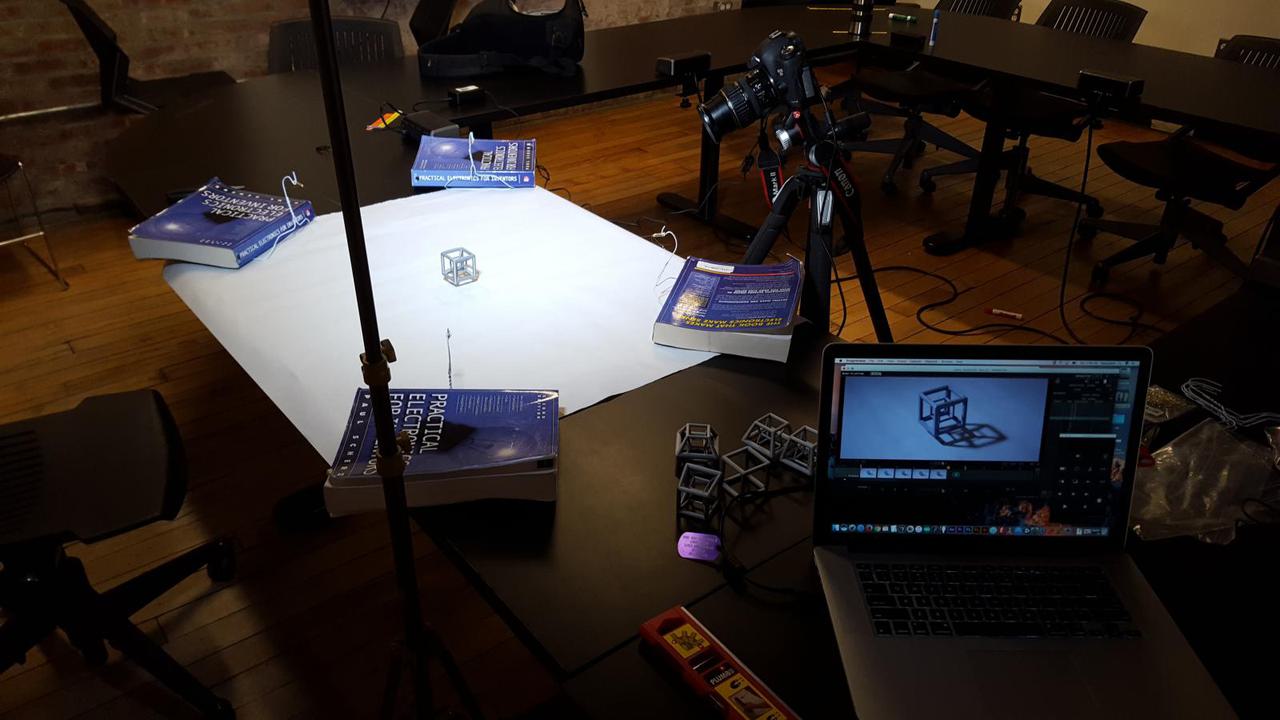 setup for photographing the animated hypercube with camera pointing at white sheet of paper with a hypercube floating a few inches above the paper.