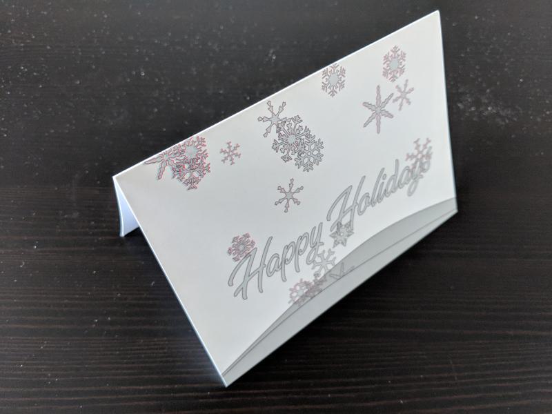 holiday greeting card that says "Happy Holidays" across the front and shows snowflakes falling from the sky