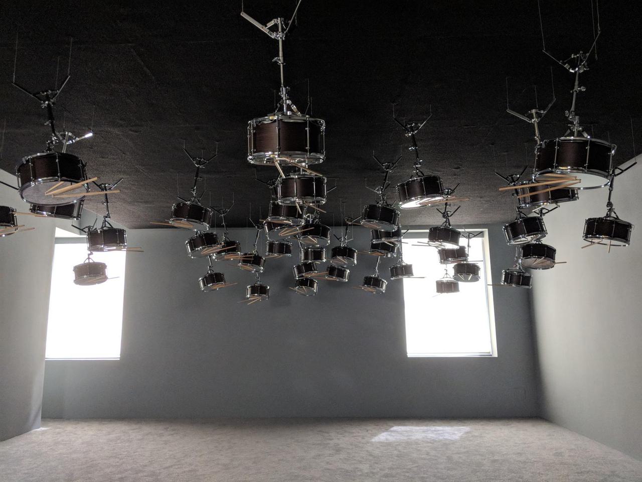 empty room with several dozen snare drums attached to the ceiling.