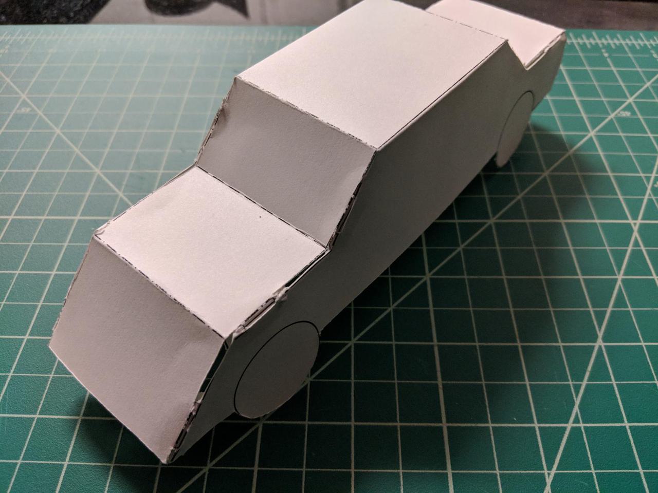 Closeup of assembled paper car sitting on a green cutting mat.