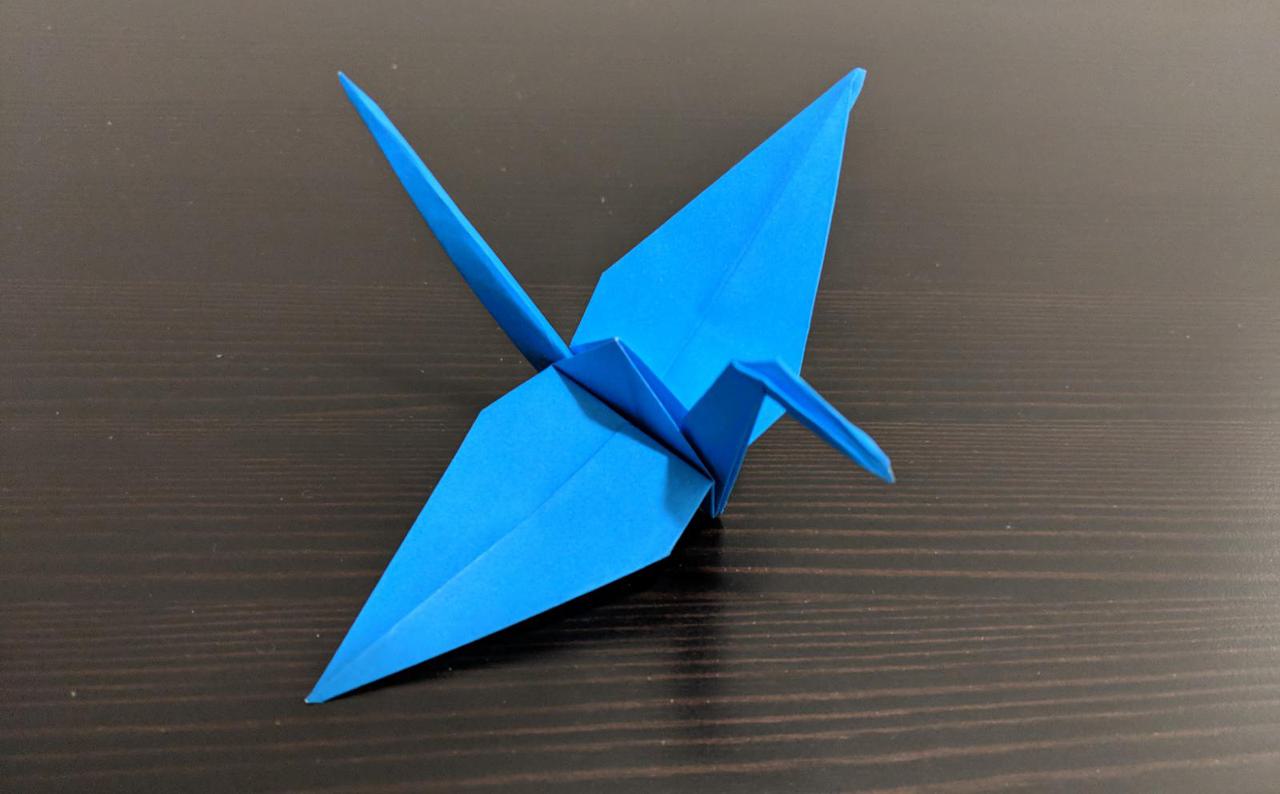 origami crane, with two wide wings a neck and head in the front and a long thin tail in the back.
