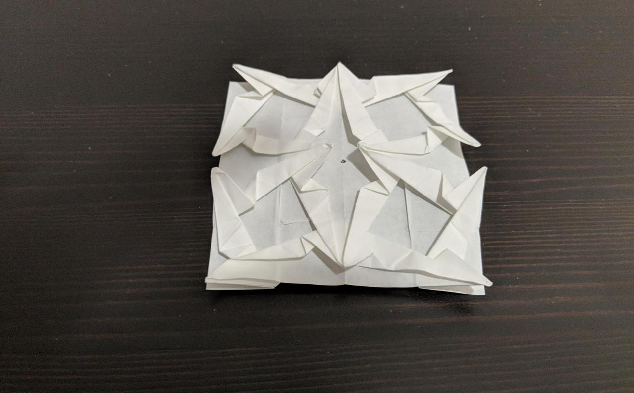 four star-like shapes folded into a single square piece of paper.
