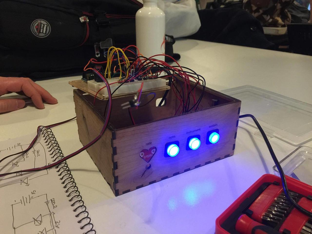 Wooden box sitting on table with connected button wires and buttons lit up