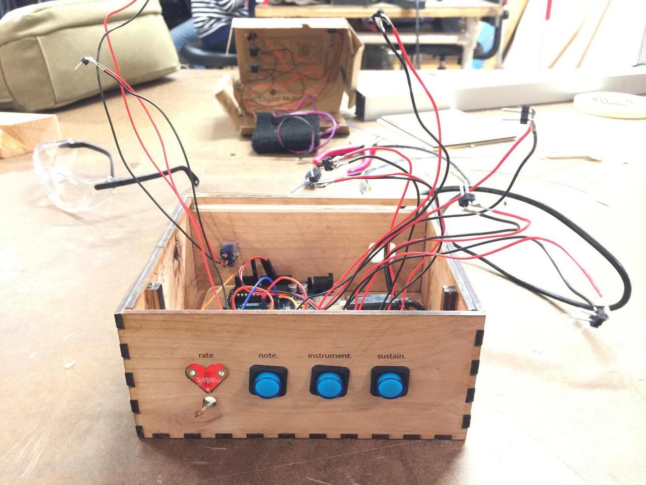 Wooden box sitting on table with button wires sticking out of it