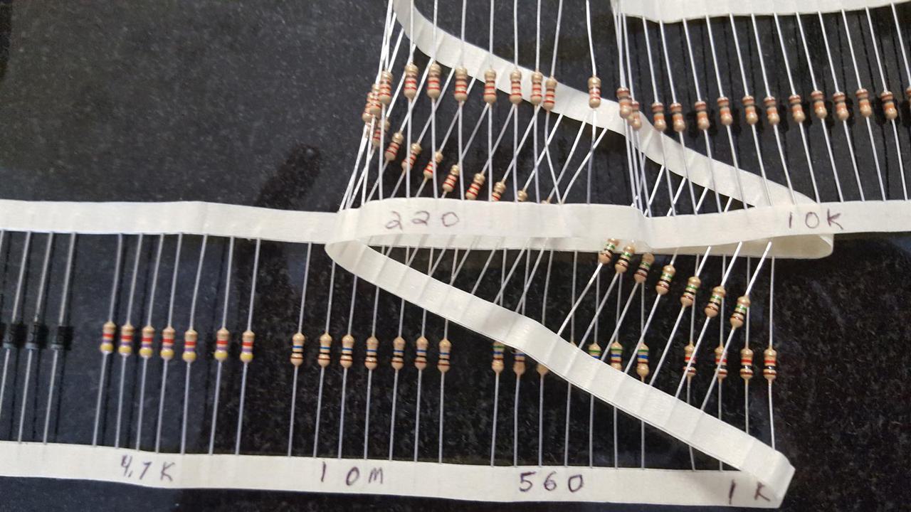 collection of resistors held in place with tape and their resistance numbers written on the tape