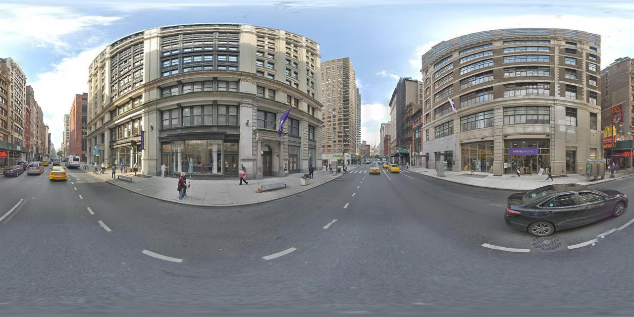 equirectangular image of 721 broadway, showing buildings everywhere and a road with cars on it.