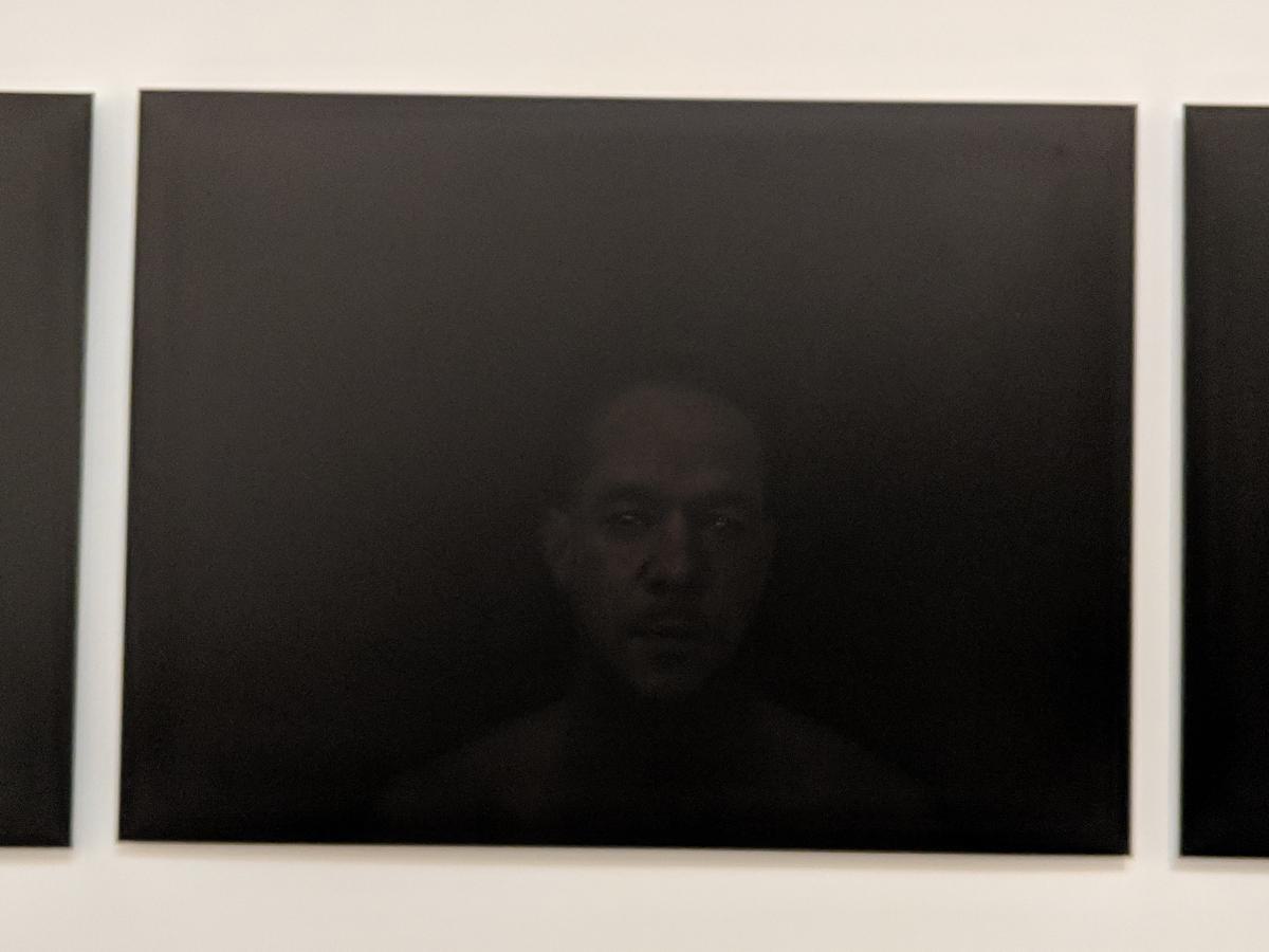black canvas with very dark image of human face.