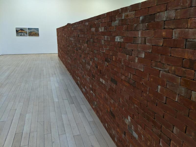Large wall made of neatly stacked bricks in the center of a room
