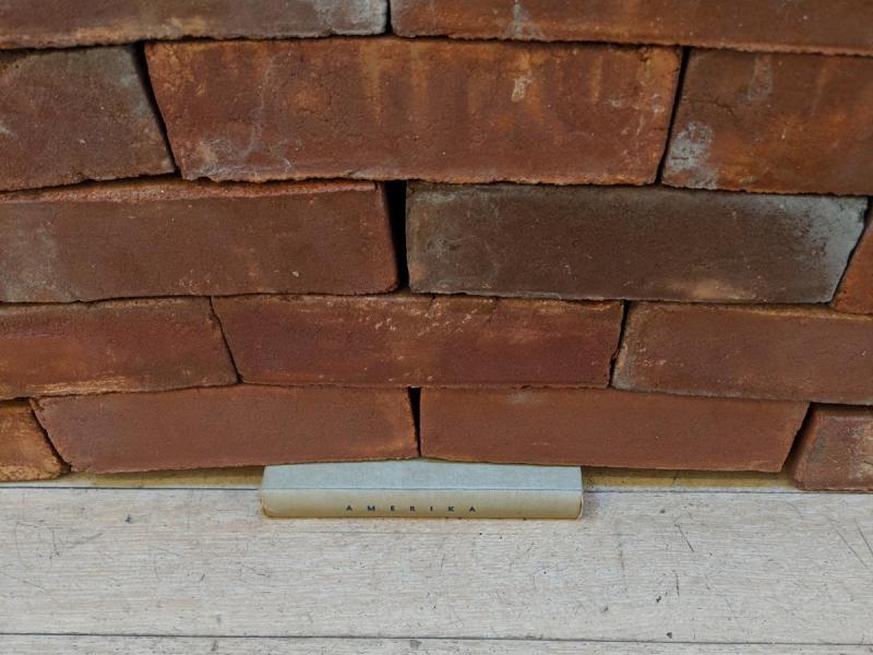 Neatly stacked bricks on the floor with a small copy of Kafka's novel Amerika underneath the bricks