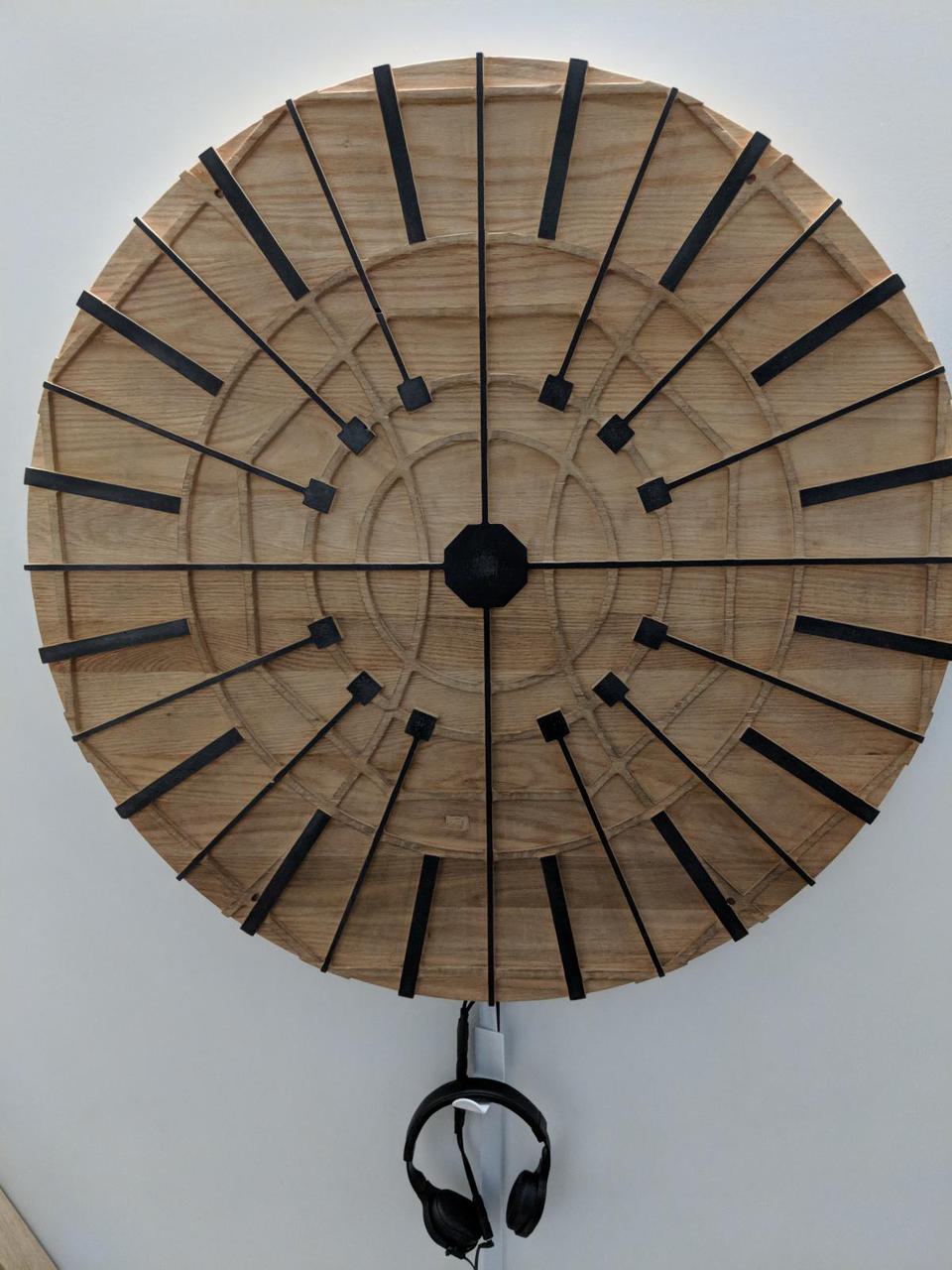 circular wood on wall with black lines created with conductive paint extending from edges to center
