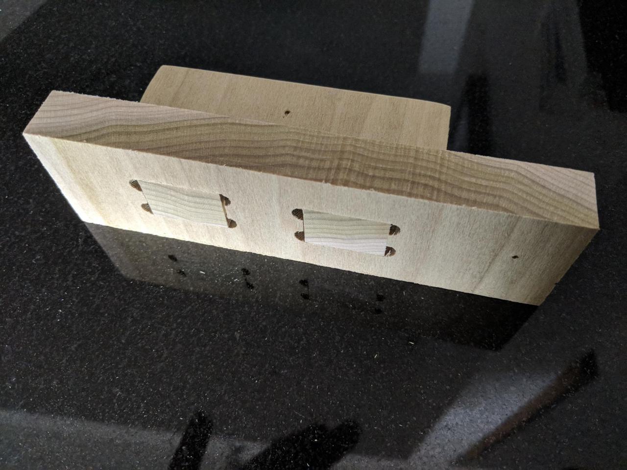 Two pieces of 0.5 inch wood joined together. The wood with the protrusions is inserted into the one with the holes. The view is from the side.
