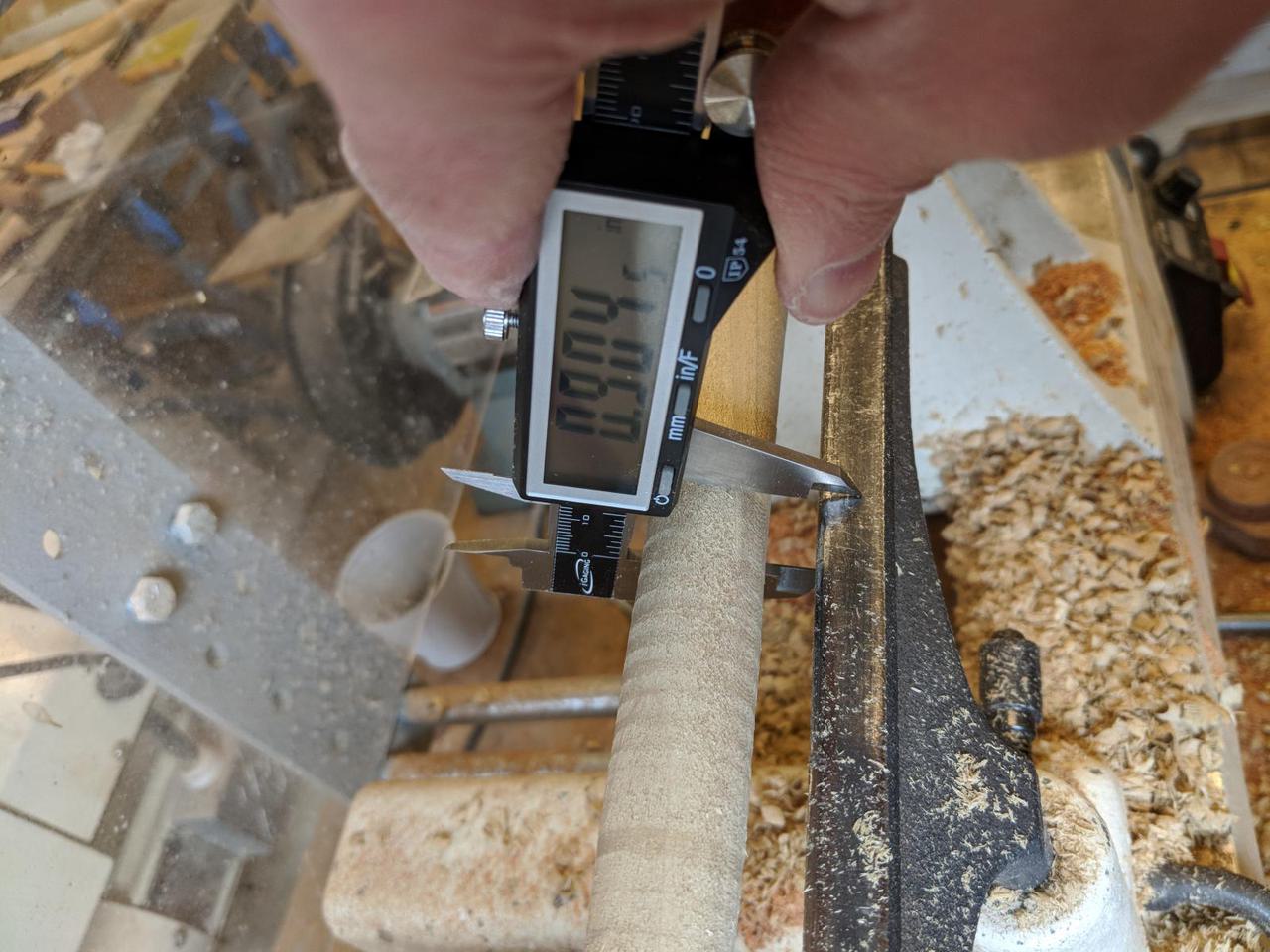 digital calipers measuring width of cylinder.