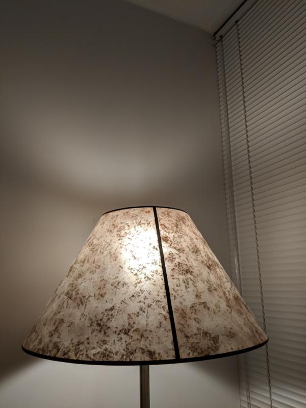 Standing lamp shining a bright light onto the wall and venetian blinds