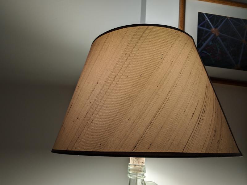 Table lamp shining a bright light onto the wall and picture on wall.