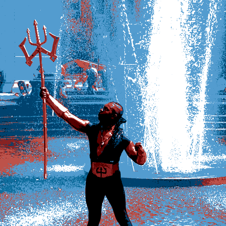 Somebody dressed as Poseidon, holding Poseidon's staff, while standing in a fountain.