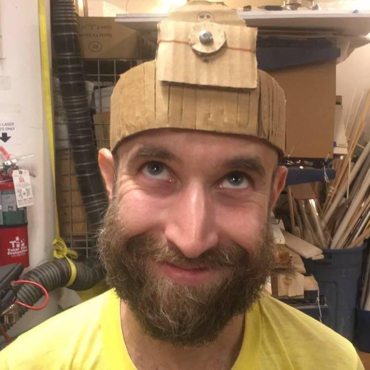 Max, smiling and looking up at the odd cardboard hat sitting on his head.