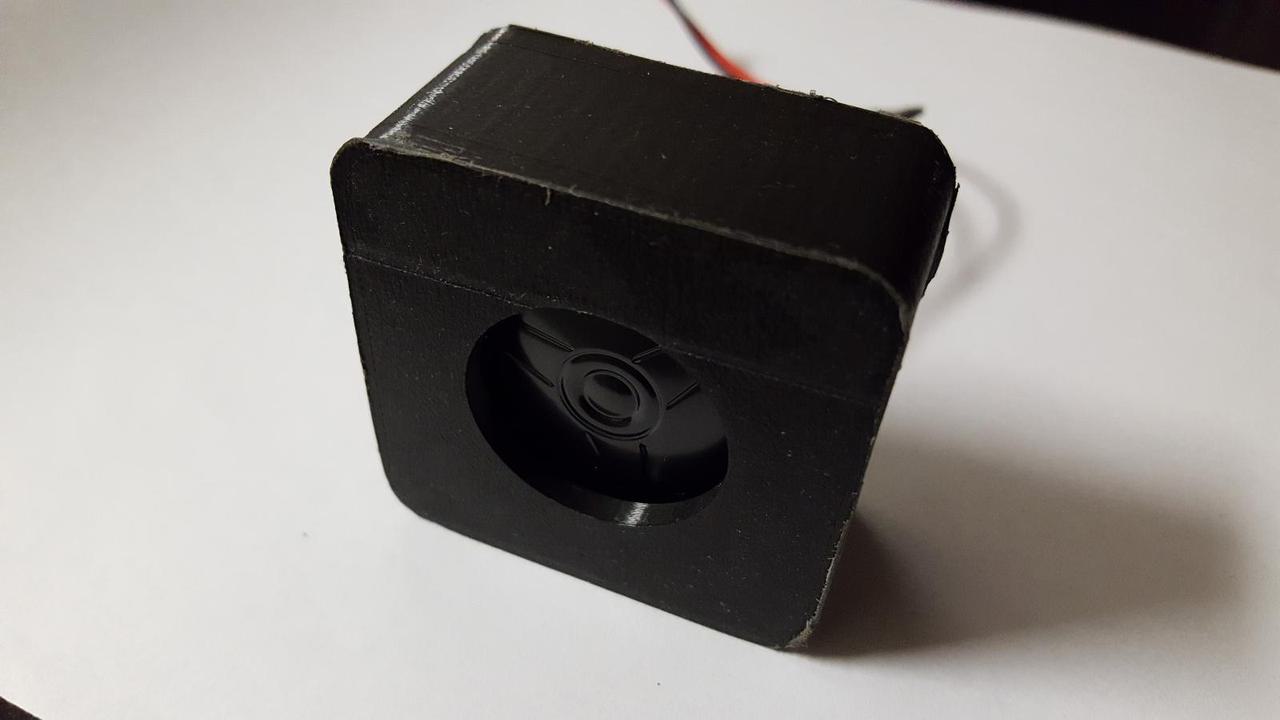 black 3D printed cube-shaped speaker case with small speaker inside