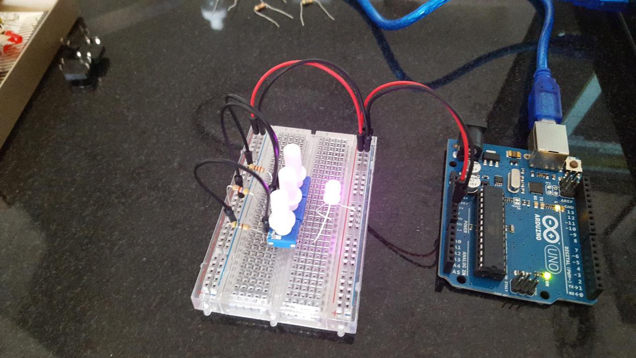 Arduino, 3 potentiometers, 3 resistors on breadboard, and brightly lit LED