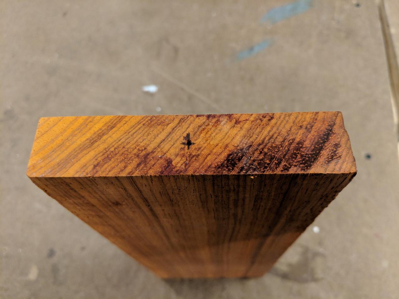 end of piece of wood with small 'x' in the center.
