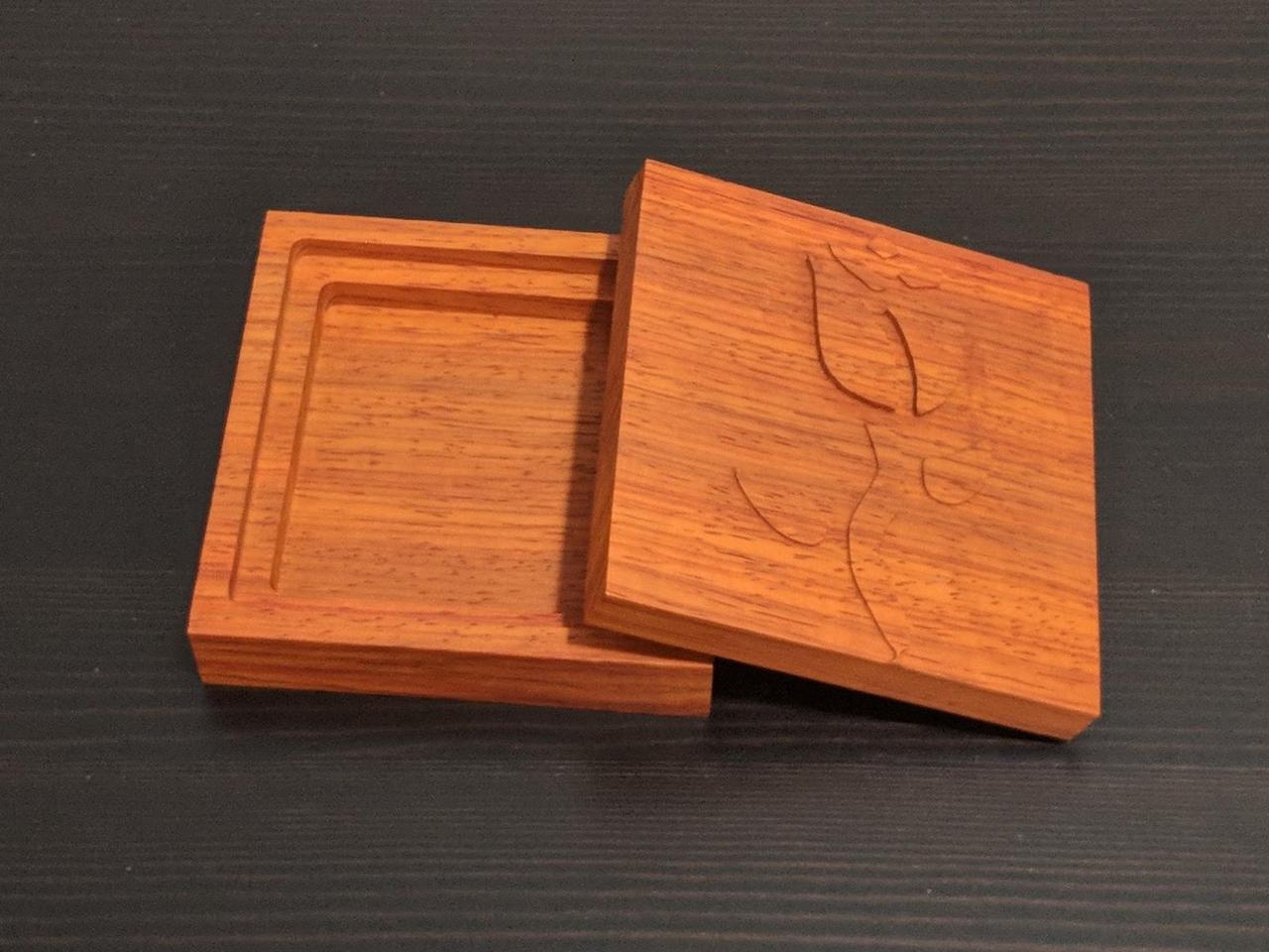 square wooden box with lid leaning on edge of box.