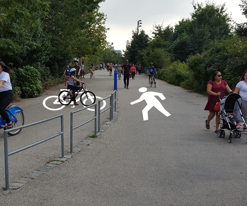 Bike and pedestrian path in park. A painted silhouette of a bike and a person are digitally added to the ground to the left and right sides of the path.