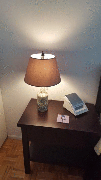 animation showing the lamp sitting on a nightstand. It is on in the first frame, off in the second, and the third shows a closeup of the lamp base, showing the gravel inside the bottle.