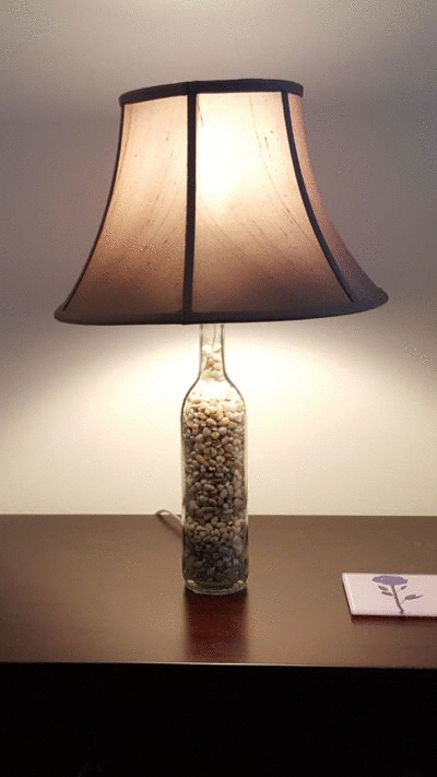 animation showing the lamp sitting on a nightstand. It is on in the first frame, off in the second, and the third shows a closeup of the lamp base, showing the gravel inside the wine bottle base.